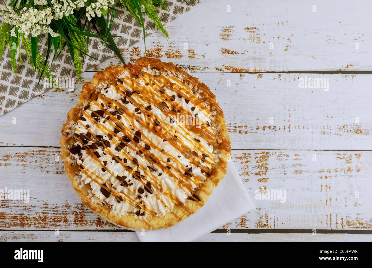 Torta cremoso con condimento al cioccolato al caramello su tavolo di legno bianco. Vista dall'alto. Foto Stock