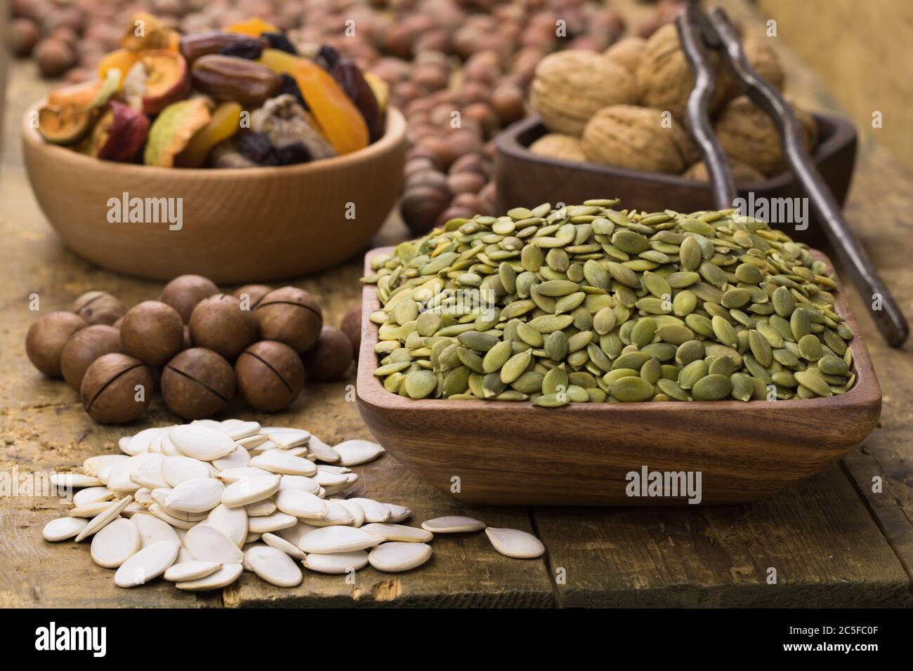 semi di zucca sbucciati in ciotola su tavola di legno. Alimenti utili per vegetariani e vegani. Foto Stock