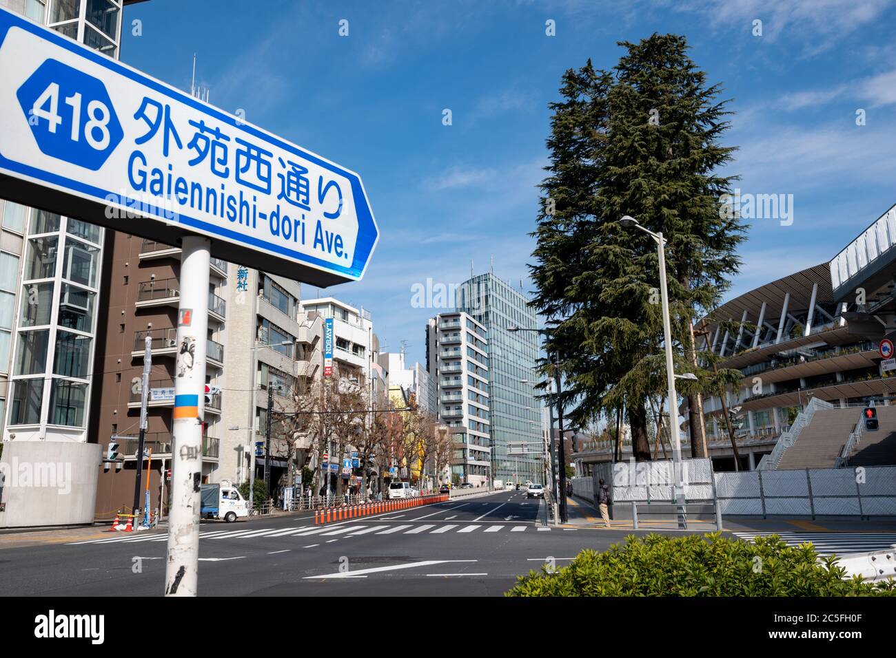 Cartello stradale di Gaiennishi-dori Ave., edifici della città, strada quasi vuota e il nuovo Stadio Nazionale. Tokyo, Giappone. Foto Stock
