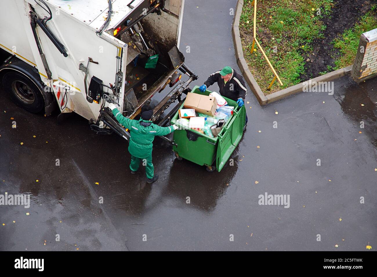 rimozione dei rifiuti in zona residenziale, spazzatura uomini che caricano rifiuti domestici in camion rifiuti Foto Stock