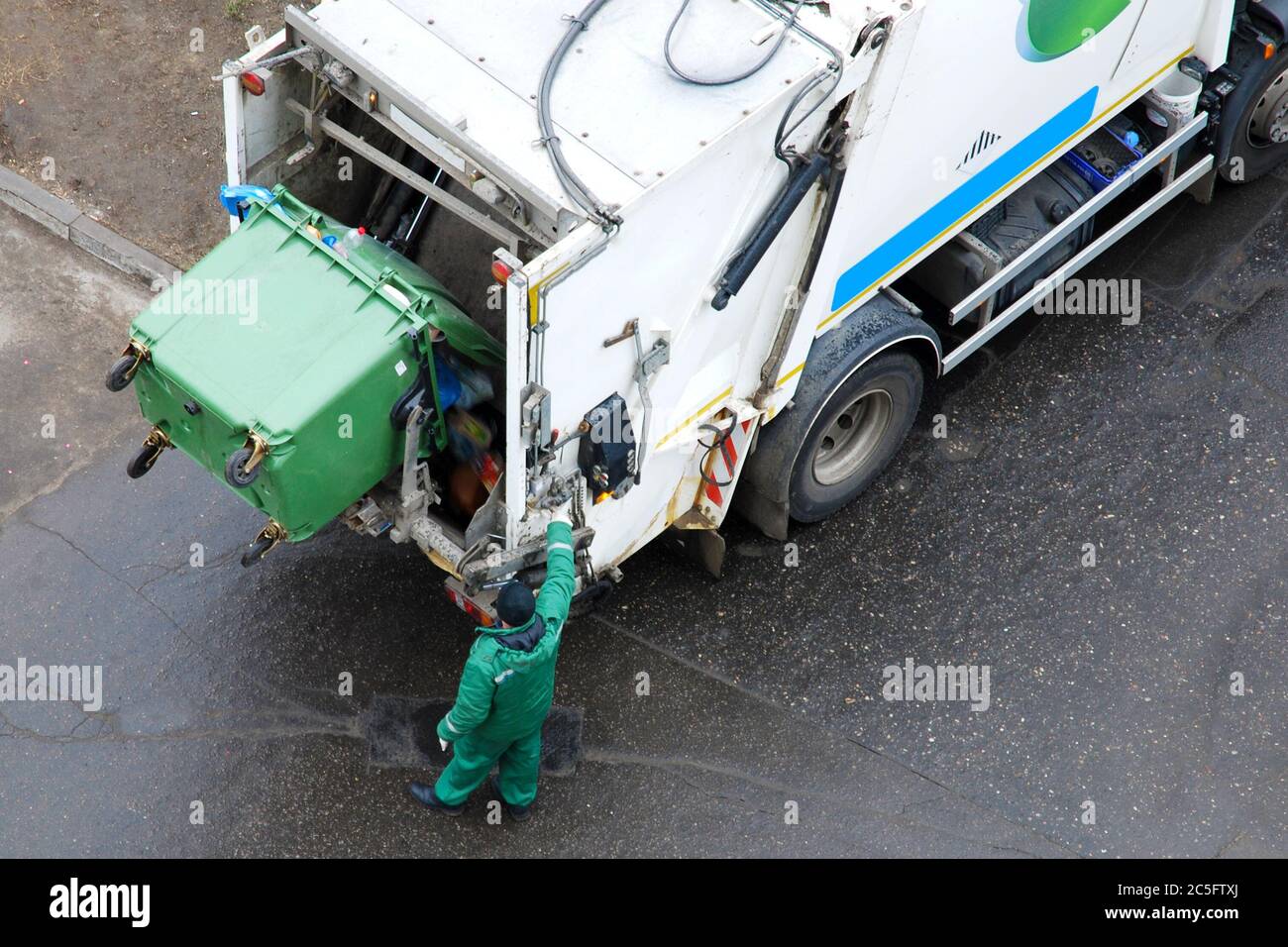 Spazzatura uomo che aziona il camion della spazzatura in zona residenziale, rimozione quotidiana della spazzatura Foto Stock