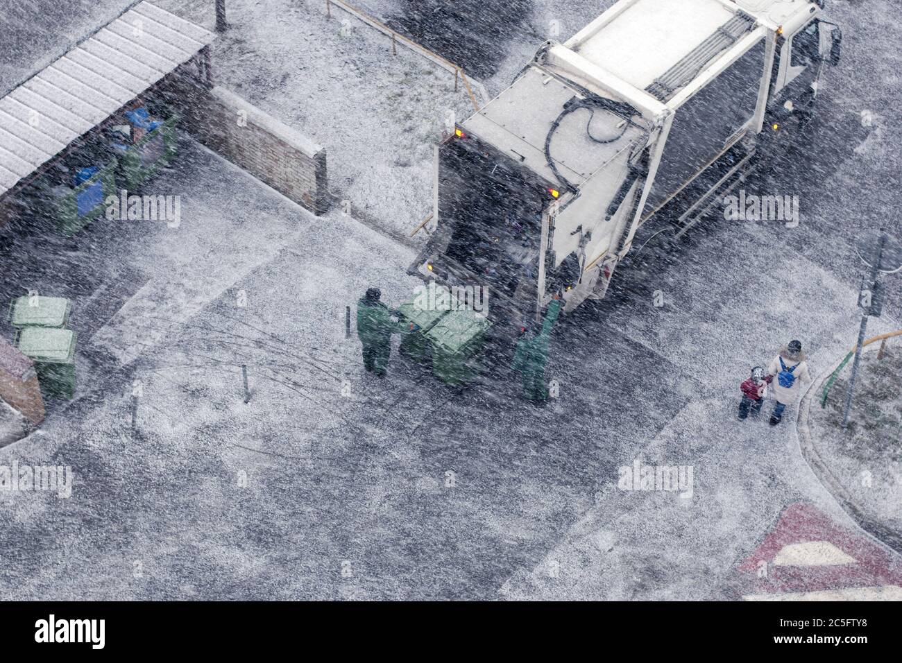 Garbage uomini in tempesta di neve che lavorano in zona residenziale Foto Stock