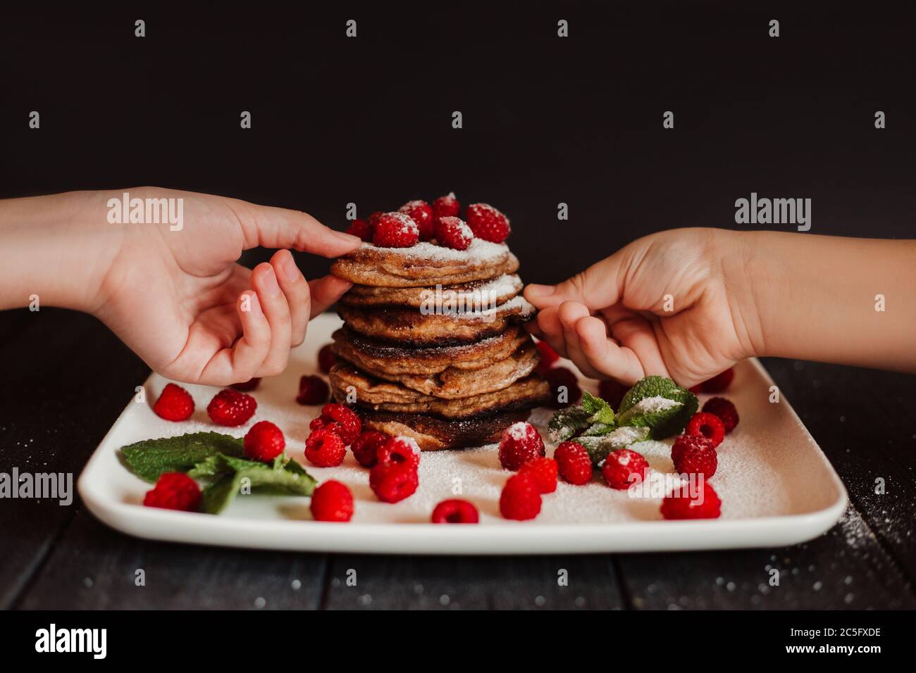 Frittelle al cioccolato con lamponi freschi e menta su sfondo nero Foto Stock