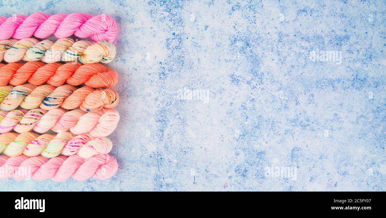 Un bordo di filati rosa su uno sfondo blu puntinato Foto Stock