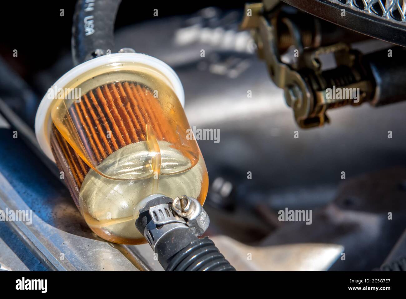 Un filtro carburante in un'auto. La benzina può essere vista nel filtro. Vista in primo piano. Foto Stock