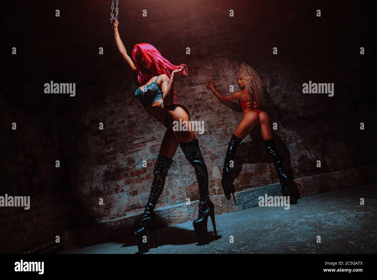 Due sexy ballerine donne in interni scuri con parete in mattoni Foto Stock
