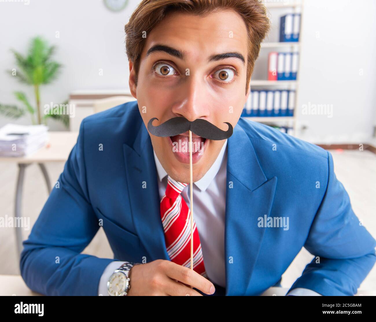 La divertente bisinessman con baffi finti in ufficio Foto Stock