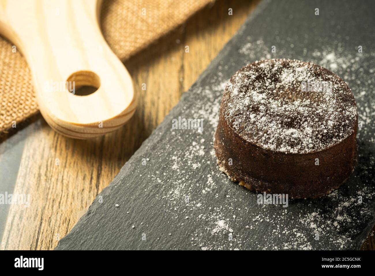 Fondente di cioccolato con zuccheri glassosi sulla parte superiore, su una piastra di ardesia nera, fuoco selettivo Foto Stock