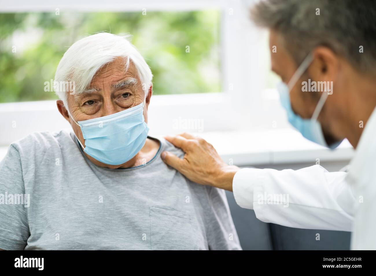 Medico che parla con un paziente anziano a casa Foto Stock
