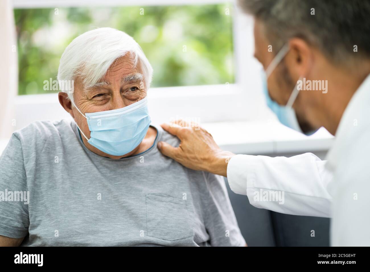 Medico che parla con un paziente anziano a casa Foto Stock
