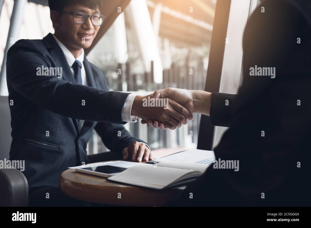 Due uomini d'affari stanno parlando e facendo gli affari sulle operazioni di affari e accosentendo scuotendo le mani nell'ufficio. Foto Stock