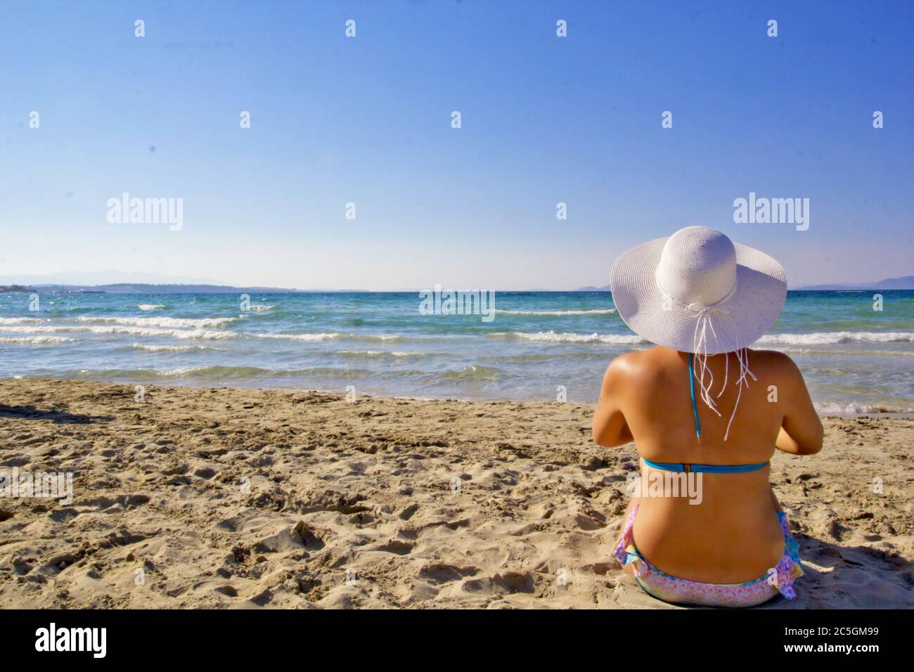 Giovane donna in cappello bianco sulla spiaggia Foto Stock