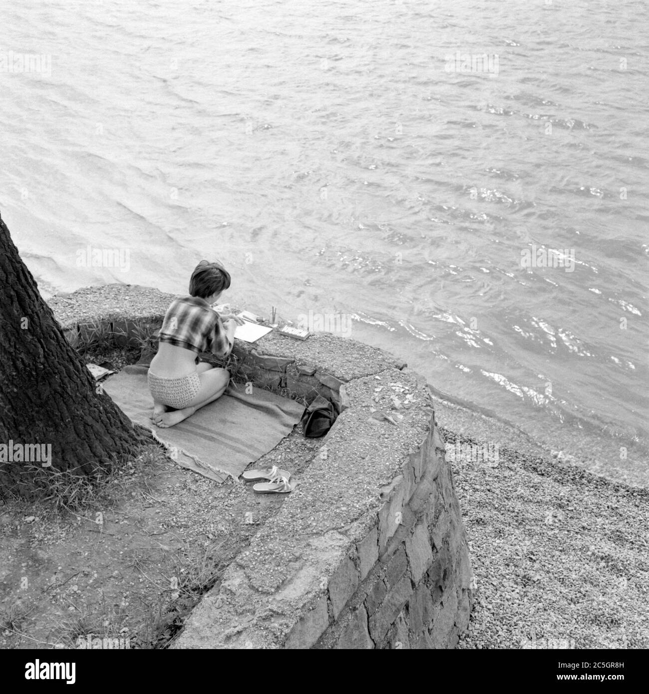 giovane donna inginocchiata mentre dipinge in un fiume 1960 ungheria Foto Stock