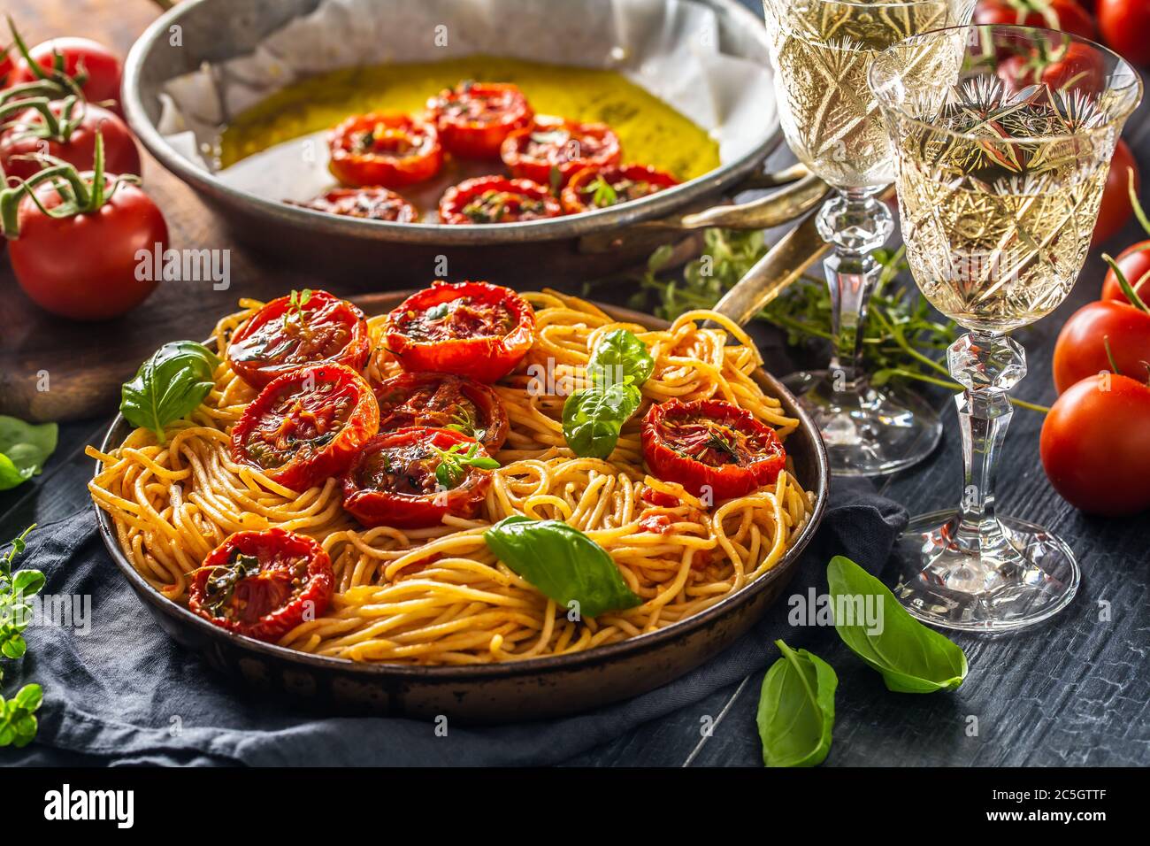 Spaghetti di pasta italiana con pomodori arrostiti timo di basilico origano e vitigno bianco Foto Stock