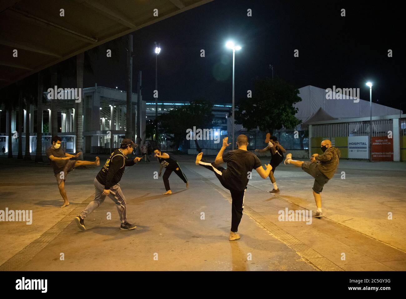 02 luglio 2020, Brasile, Rio De Janeiro: Un gruppo di persone pratica capoeira di fronte allo stadio Maracanã, con l'ospedale da campo per il trattamento di pazienti COVID19 in background, durante la partita di calcio di volta Redonda e Resende. Le partite di calcio si sono svolte nuovamente a Rio de Janeiro, l'unico stato del paese che consente la ripresa dello sport, nonostante l'elevato numero di infezioni e morti causate dalla malattia che sono ancora registrati quotidianamente nello stato e nel paese. Il Brasile ha registrato più di 47,000 nuovi casi di Covid-19 nelle ultime 24 ore, portando il totale n Foto Stock