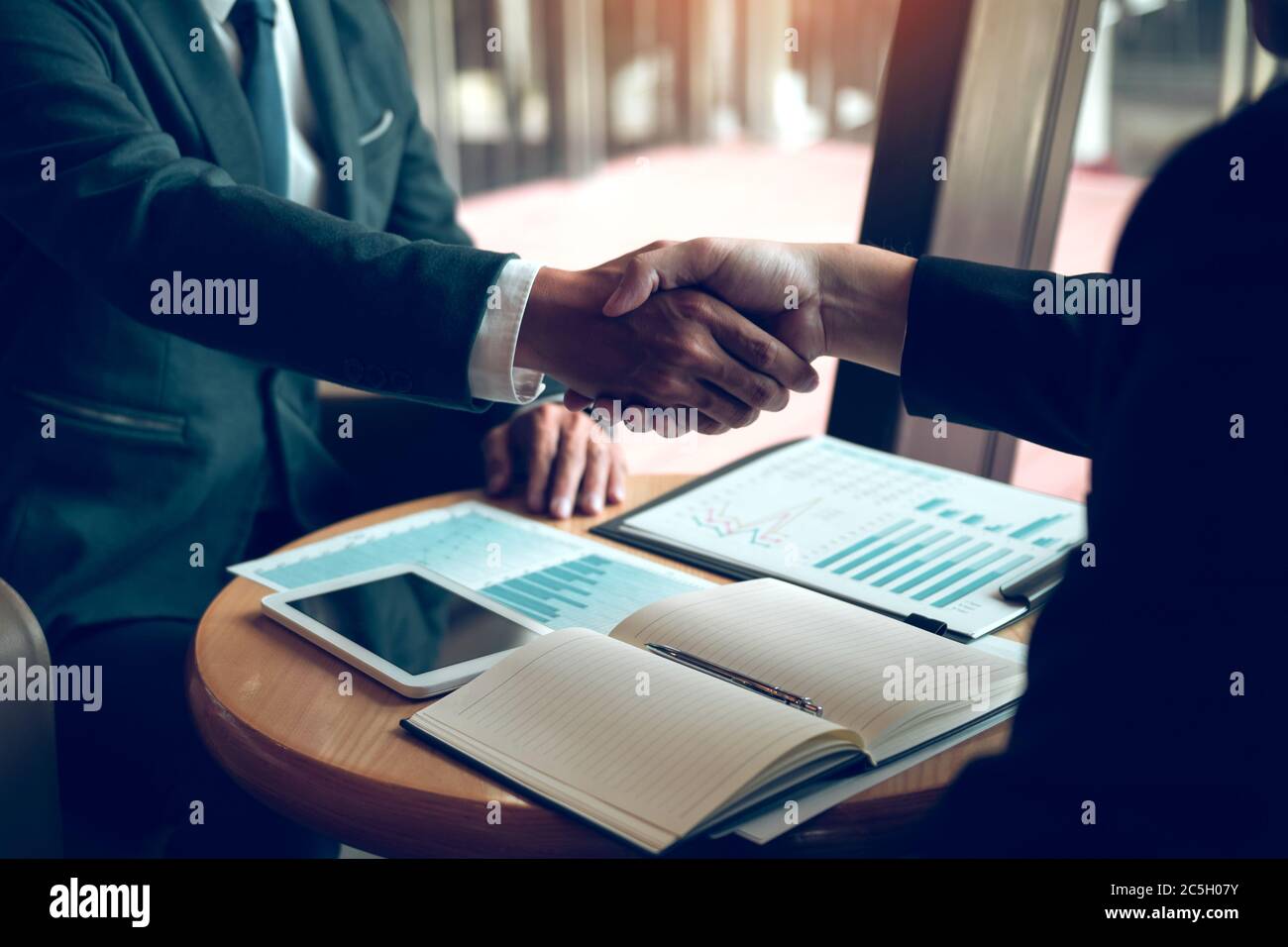 Due uomini d'affari stanno parlando e facendo gli affari sulle operazioni di affari e accosentendo scuotendo le mani nell'ufficio. Foto Stock