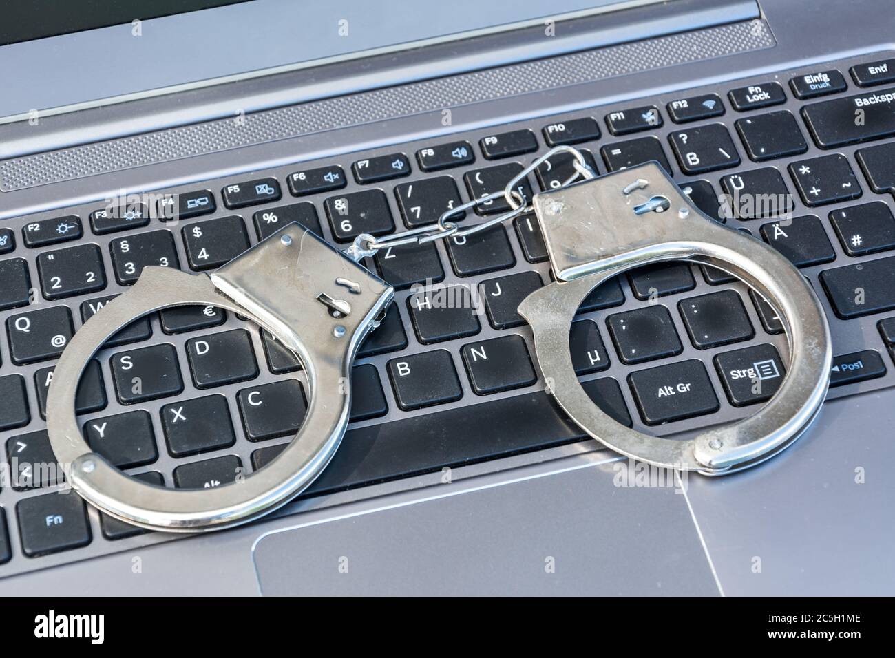 Manette giacciono sulla tastiera del computer come simbolo per il cybercrimine Foto Stock