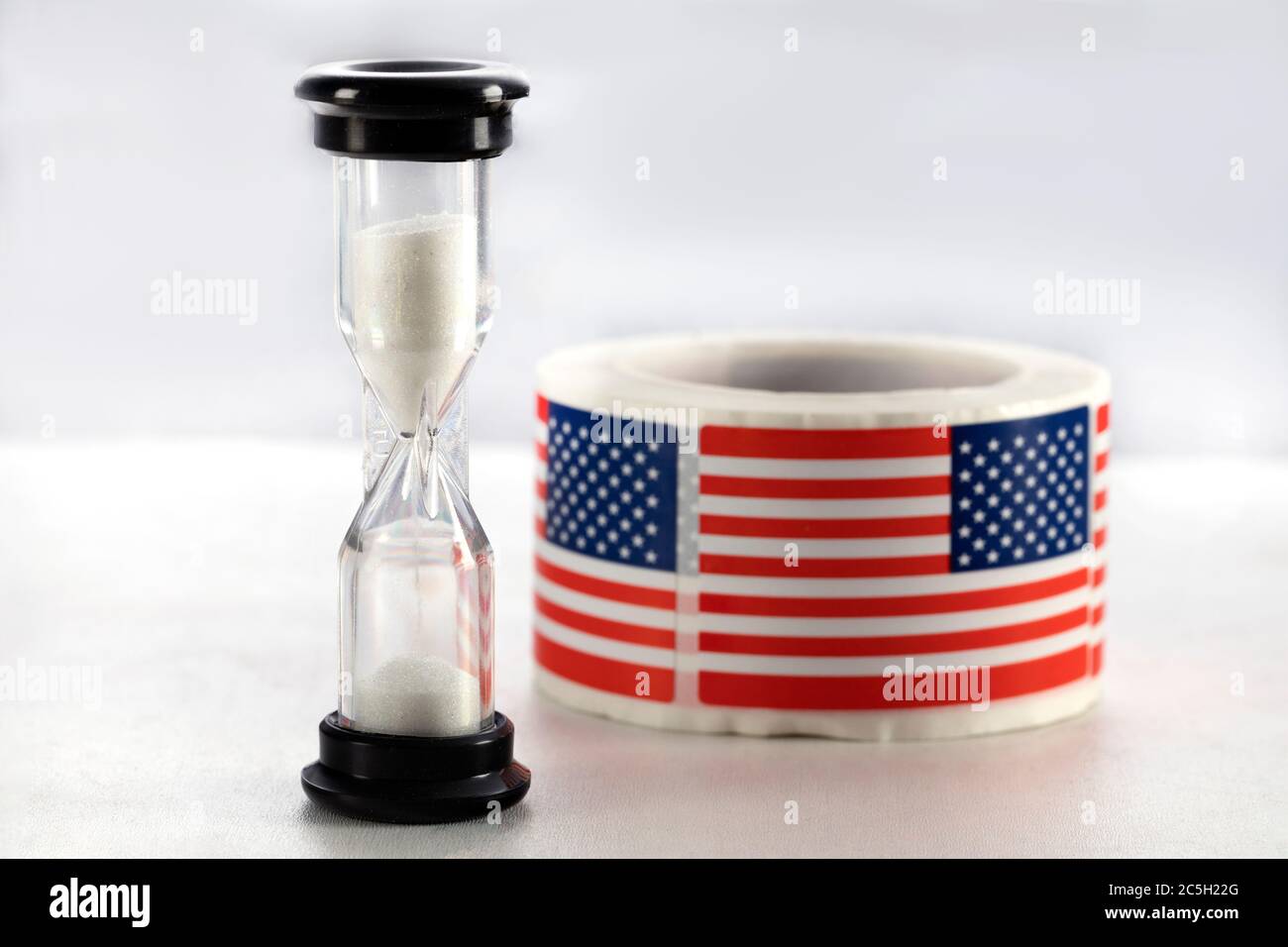 Sabbia che scorre attraverso clessidra misurazione del tempo di passaggio con la bandiera degli Stati Uniti. Il tempo sta per esaurire Foto Stock