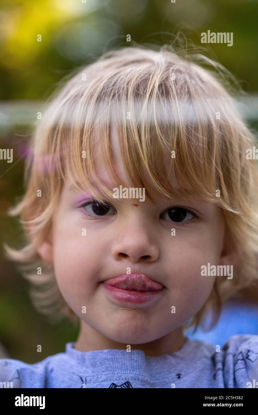 Giovane ragazzo prescolare che soffia bolle iridate giganti in un ambiente cortile Foto Stock