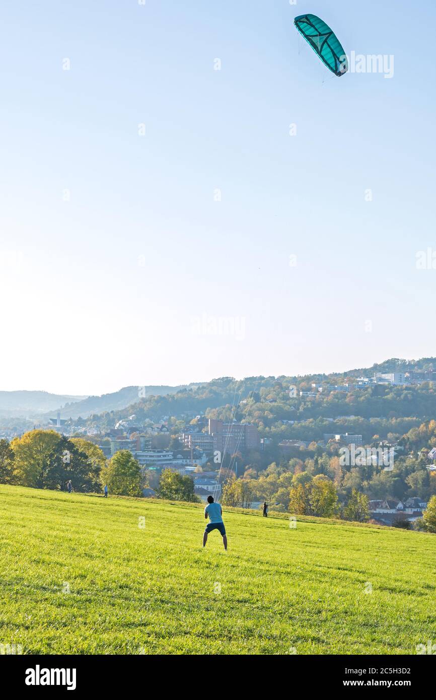L'uomo sta guidando il kite grande su un prato verde Foto Stock