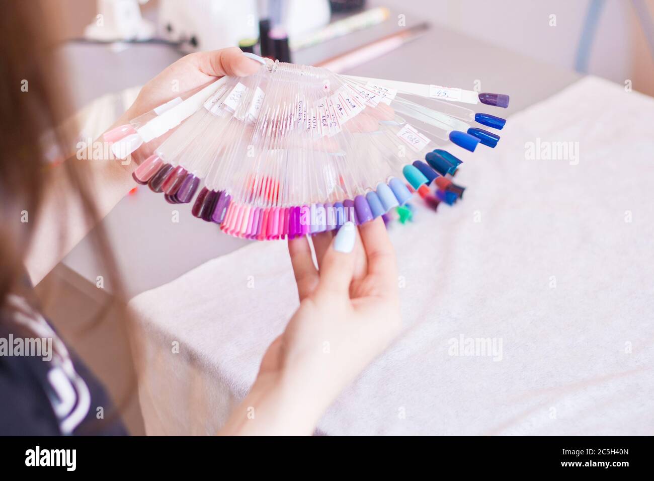 Mano giovane donna scelta del colore del chiodo. Mani e unghie manicure femminili campioni di colore, salone di bellezza. Foto Stock