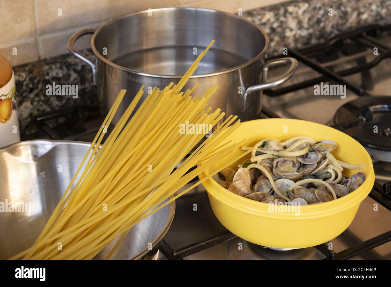 preparazione di spaghetti con vongole su un piano cottura a casa Foto Stock