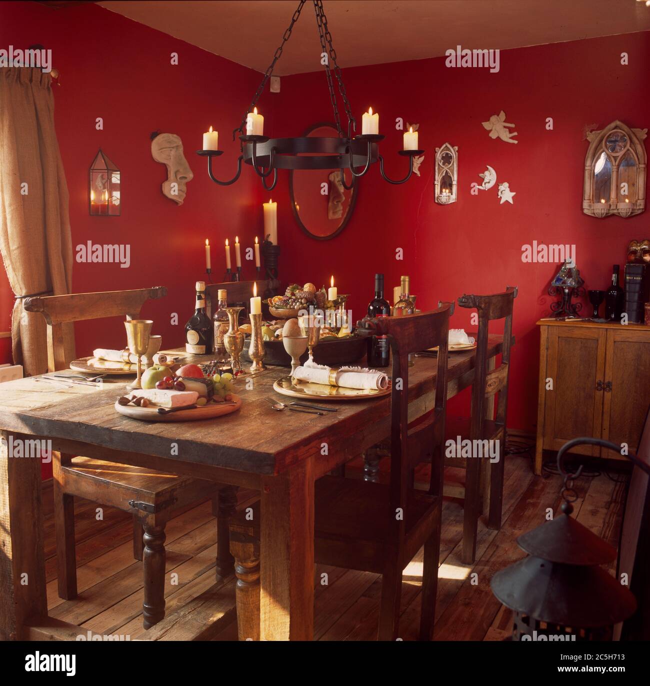 Sala da pranzo decorata in rosso caldo con candele per un pasto festivo chiaro Foto Stock