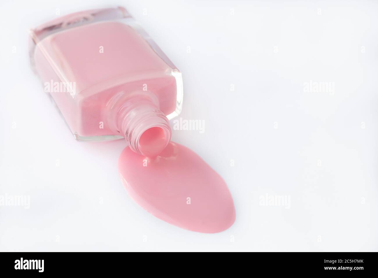 Smalto per unghie versato in bottiglia di vetro su fondo bianco, smalto rosa per manicure francese. Prodotto cosmetico. Posizione vuota per il testo. Spazio di copia, simulazione Foto Stock