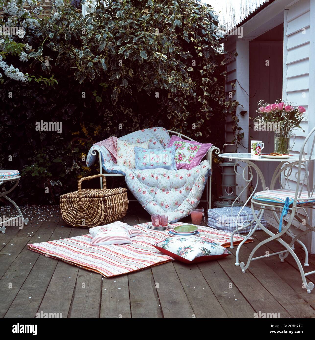 Tessuti pastello con tavolo da picnic in vimini e sedie all'esterno della casa estiva Foto Stock