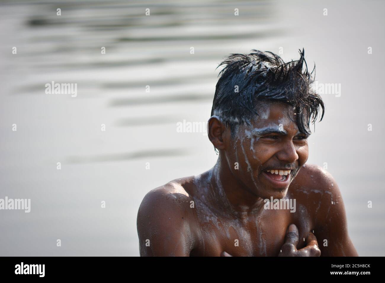 TIKAMGARH, MADHYA PRADESH, INDIA - 13 NOVEMBRE 2019: Ragazzo villaggio indiano che bagna nel fiume la mattina, lavando corpo e capelli con shampoo. Foto Stock