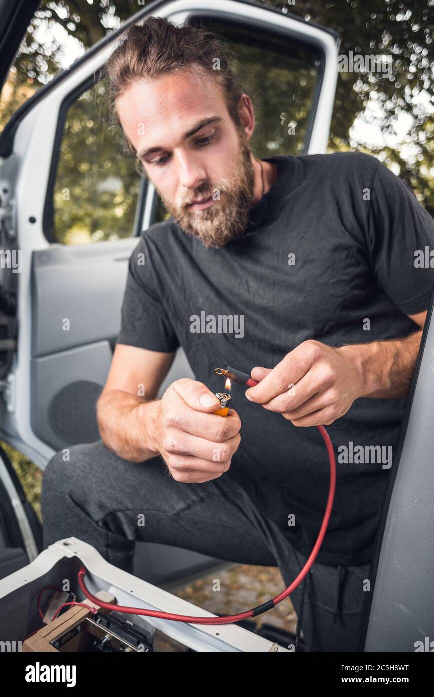 Uomo all'interno di un furgone utilizzando una guaina termorestringente su un cavo elettrico Foto Stock