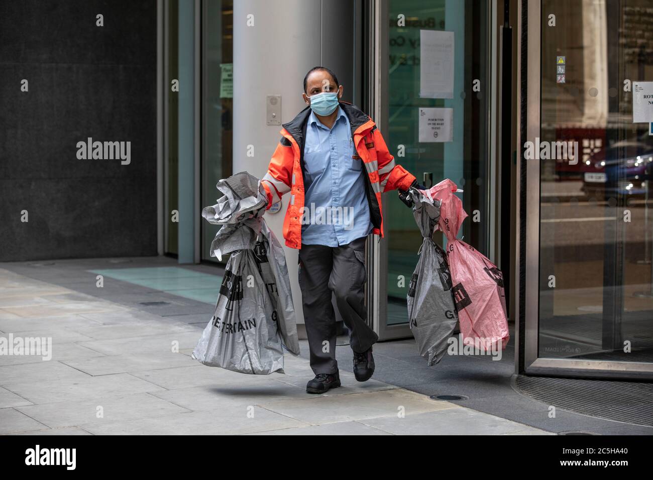 Postal Deliver worker preparandosi a caricare il suo Royal Mail Zero Emission Electric Postal Van indossando una maschera facciale nel centro di Londra, Inghilterra, Regno Unito Foto Stock