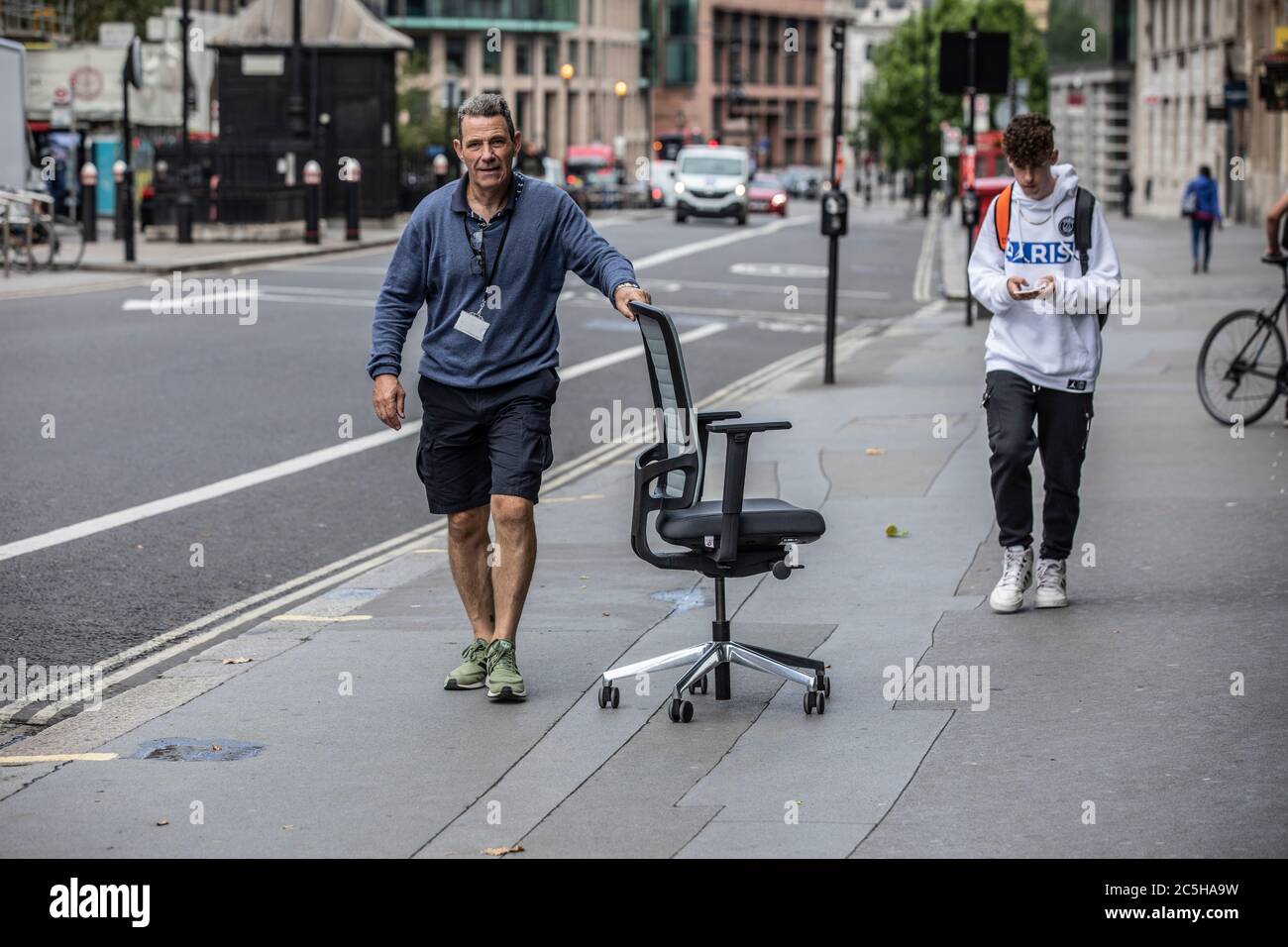 Corriere che consegna la sedia dell'ufficio lungo High Holborn, Città di Londra, Inghilterra, Regno Unito Foto Stock