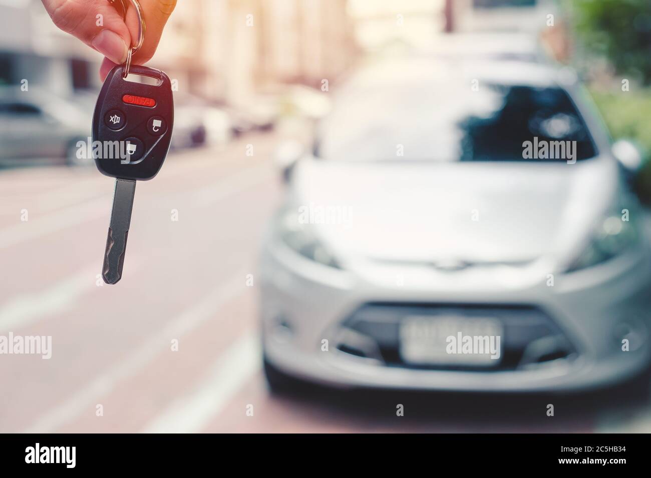 Chiave per auto closeup con pulsante del telecomando di sicurezza con sfondo sfocato per noleggiare un'auto o acquistare un nuovo concetto di auto. Foto Stock