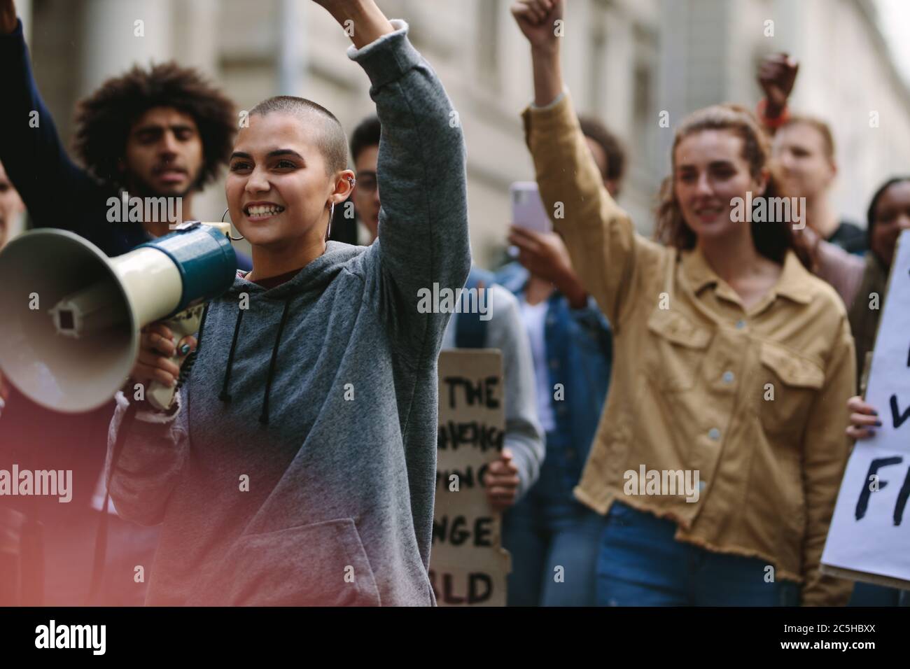 Giovane donna ribelle con megafono durante la protesta di strada. Una donna protestore urla su un corno mentre partecipa a una dimostrazione di strada. Foto Stock Giovane donna ribelle con megafono durante la protesta di strada. Una donna protestore urla su un corno mentre partecipa a una dimostrazione di strada. Foto Stock