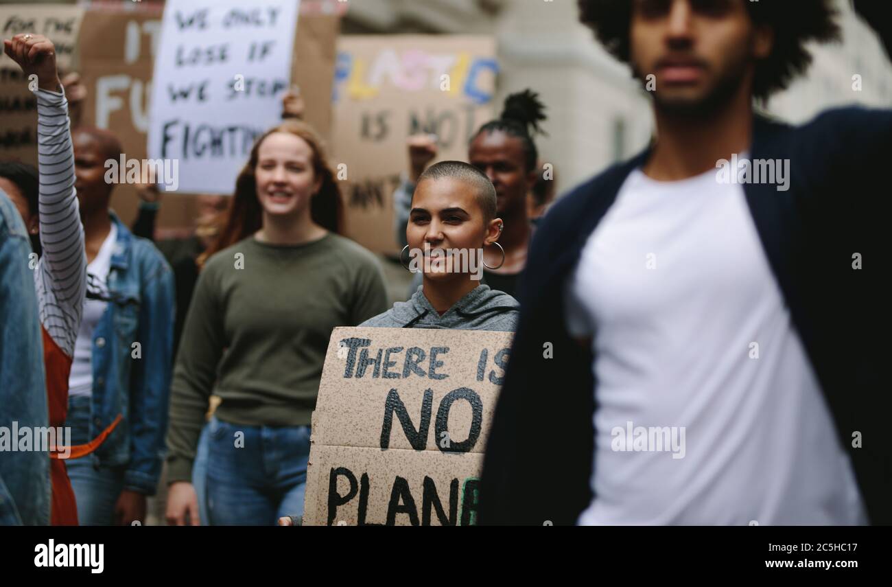 Gruppo di attivisti che marciano e protestano in città. Donna che protestava con un gruppo di persone in viaggio. Foto Stock Gruppo di attivisti che marciano e protestano in città. Donna che protestava con un gruppo di persone in viaggio. Foto Stock