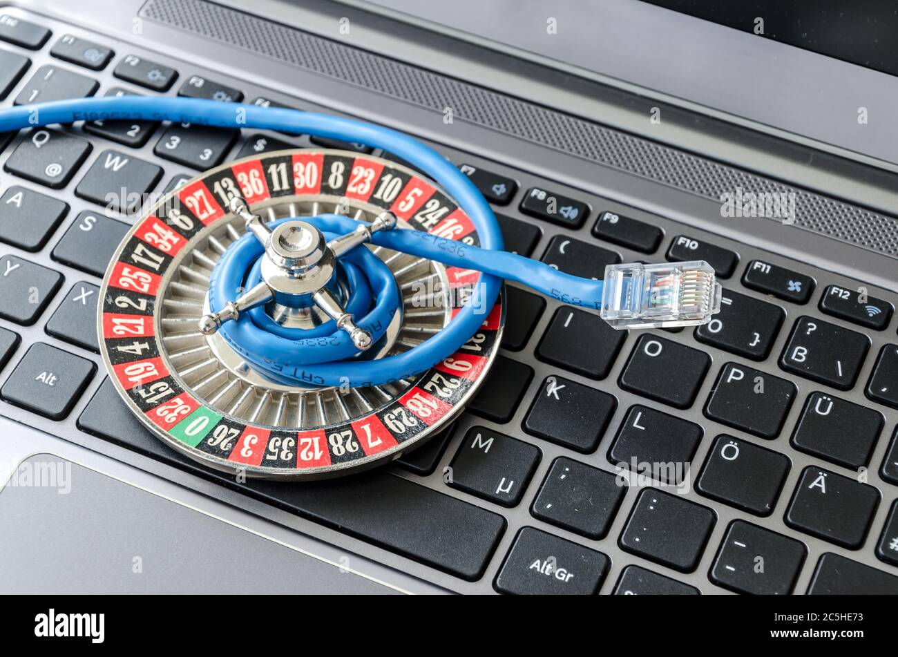 Ruota della roulette e cavo internet che giace sulla tastiera del computer simbolizzando la crittografia dei dati Foto Stock