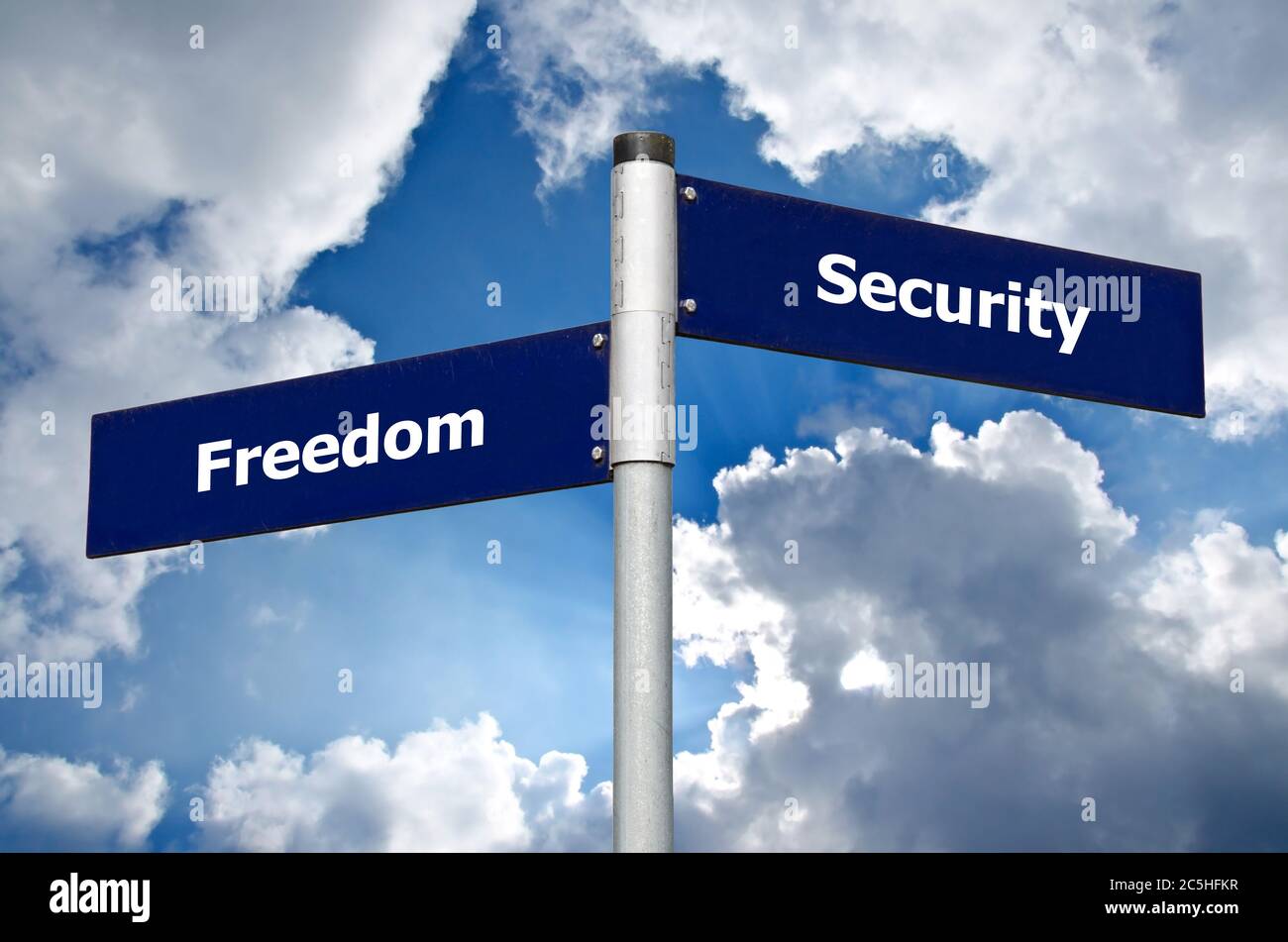 Cartello stradale di fronte alle nuvole scure che simboleggia la scelta tra "libertà" e "sicurezza" Foto Stock