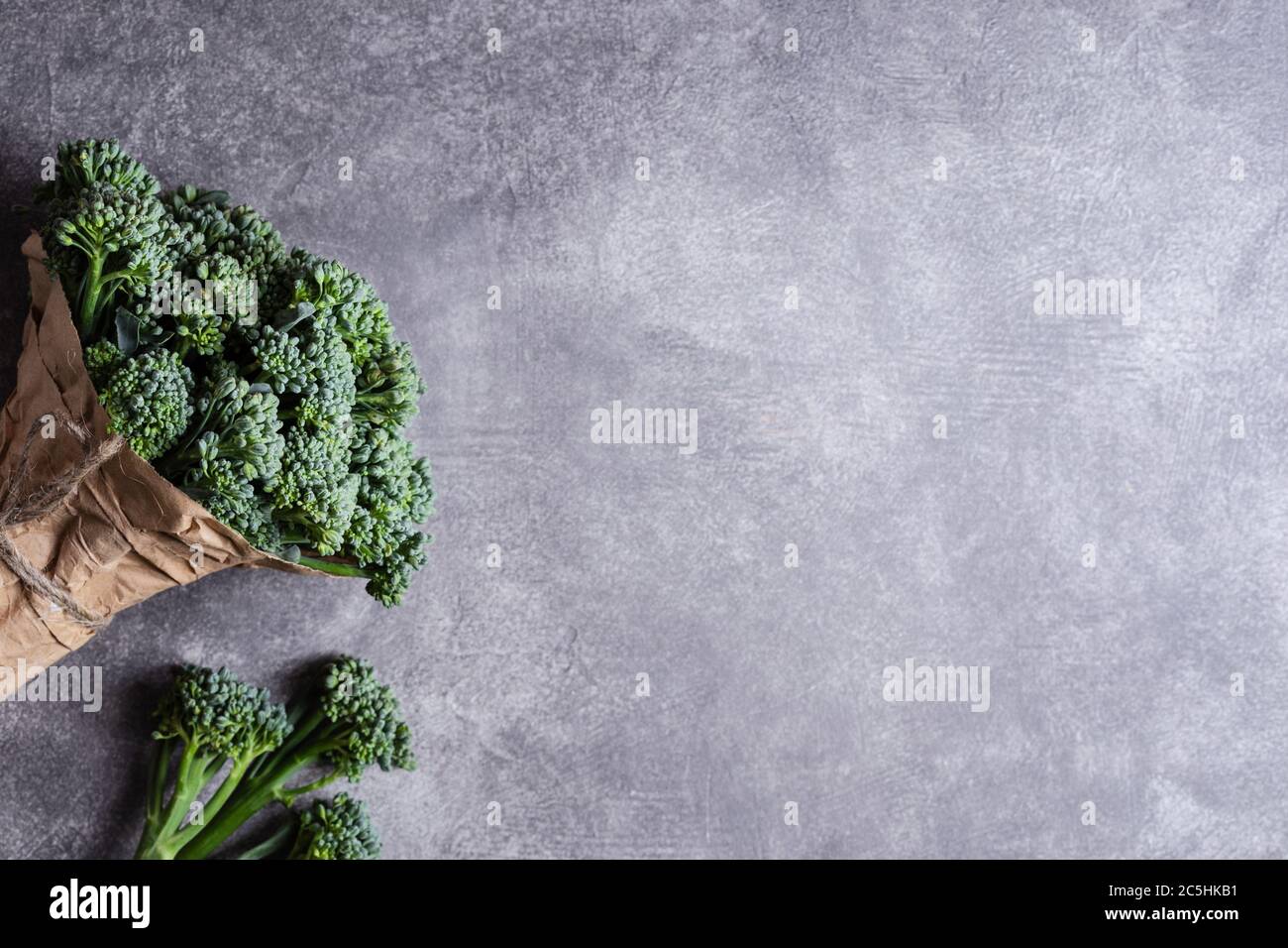 Mazzo di broccolini su fondo grigio. Vista dall'alto con spazio per la copia. Foto Stock