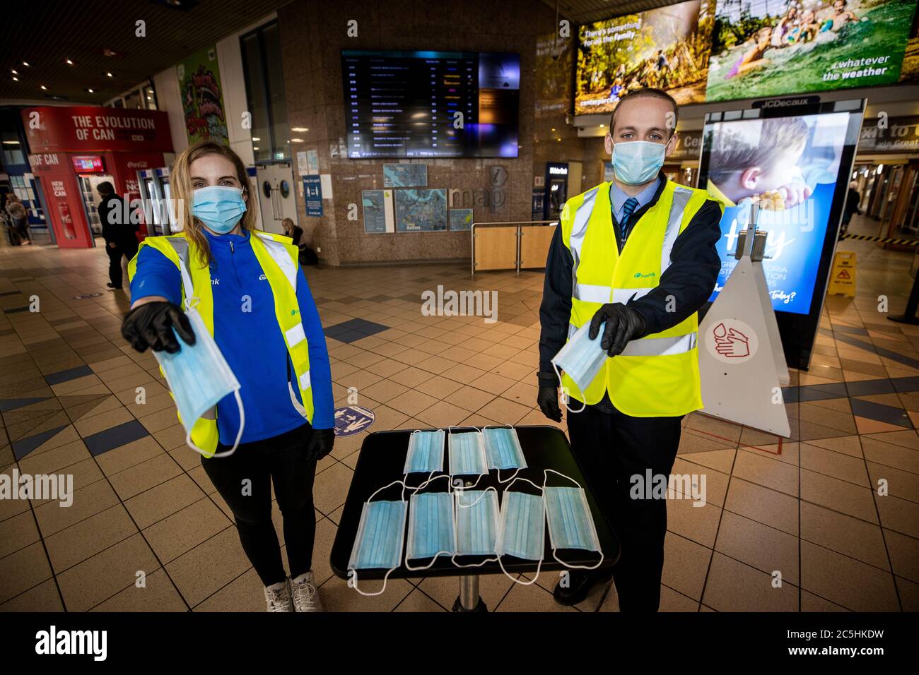 Il personale di Translink Natalie McNaly e Peter Knight consegnano la maschera all'Europa Buscenter e alla stazione ferroviaria Great Victoria Street di Belfast. Foto Stock