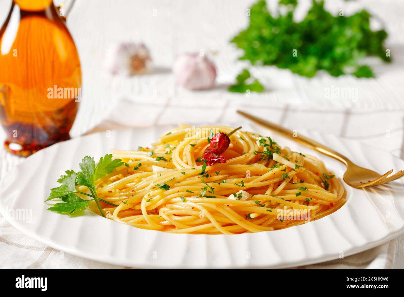 Spaghetti con la colatura di alici, Spaghetti con salsa di acciughe, pepe pimento, aglio e prezzemolo su un piatto bianco con una bottiglia di salsa di pesce a t. Foto Stock