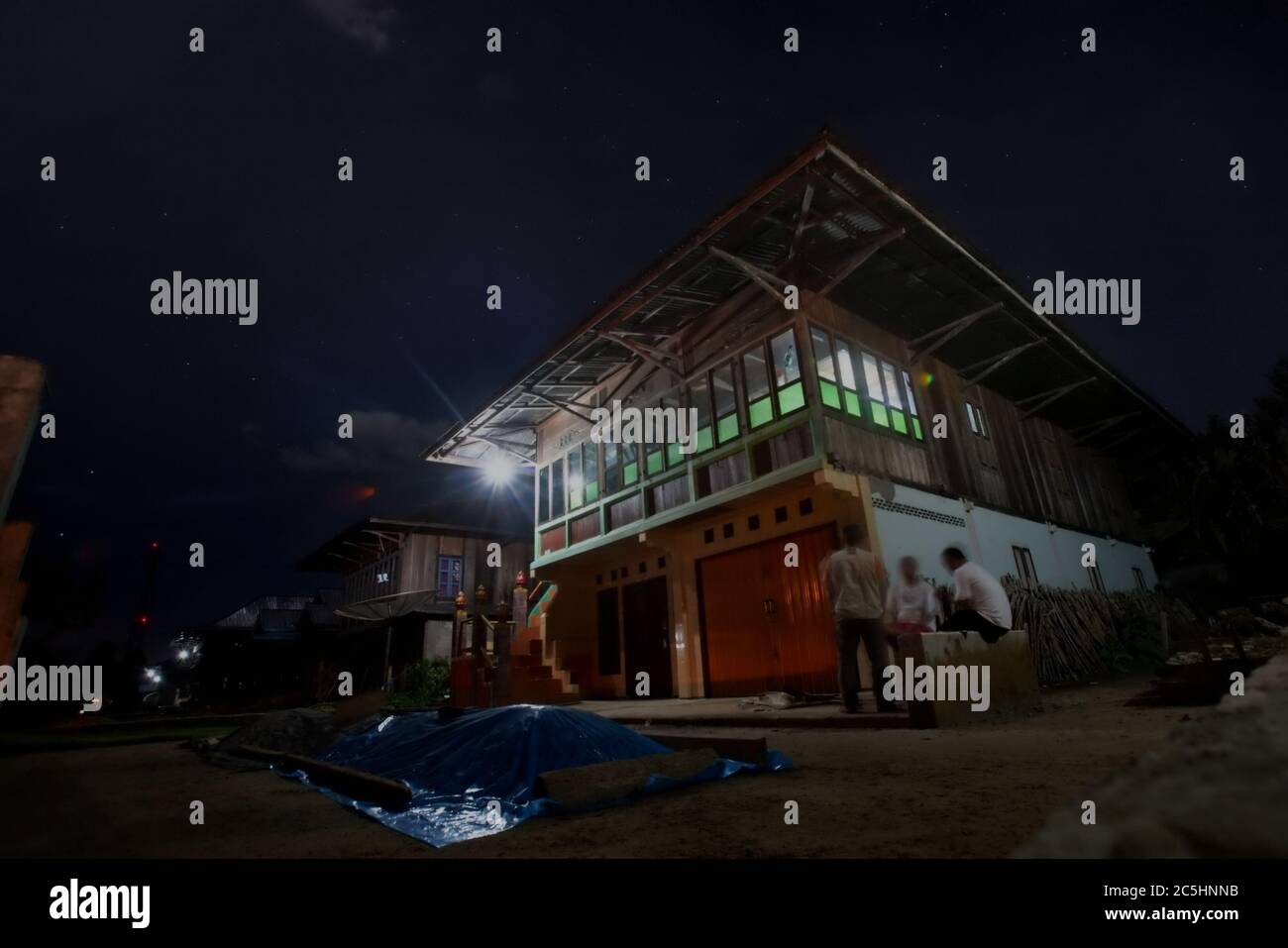 Giornalisti che hanno una conversazione con un proprietario di una casa in un quartiere residenziale costruito in stile architettonico tradizionale malese. Liwa, provincia di Lampung, Indonesia. Foto Stock