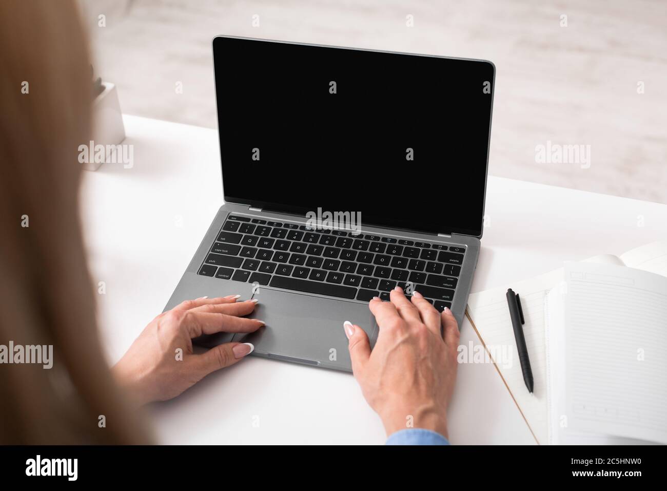 Marketing e smm. Donna lavora al laptop, vicino a notebook e penna Foto Stock