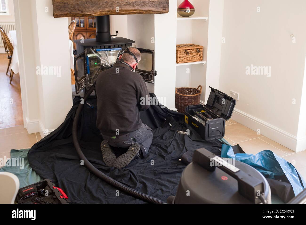 BUCKINGHAM, Regno Unito - 20 aprile 2020. Uomo spazzando legna stufa e camino con un tubo di canna fumaria in una casa, Regno Unito Foto Stock