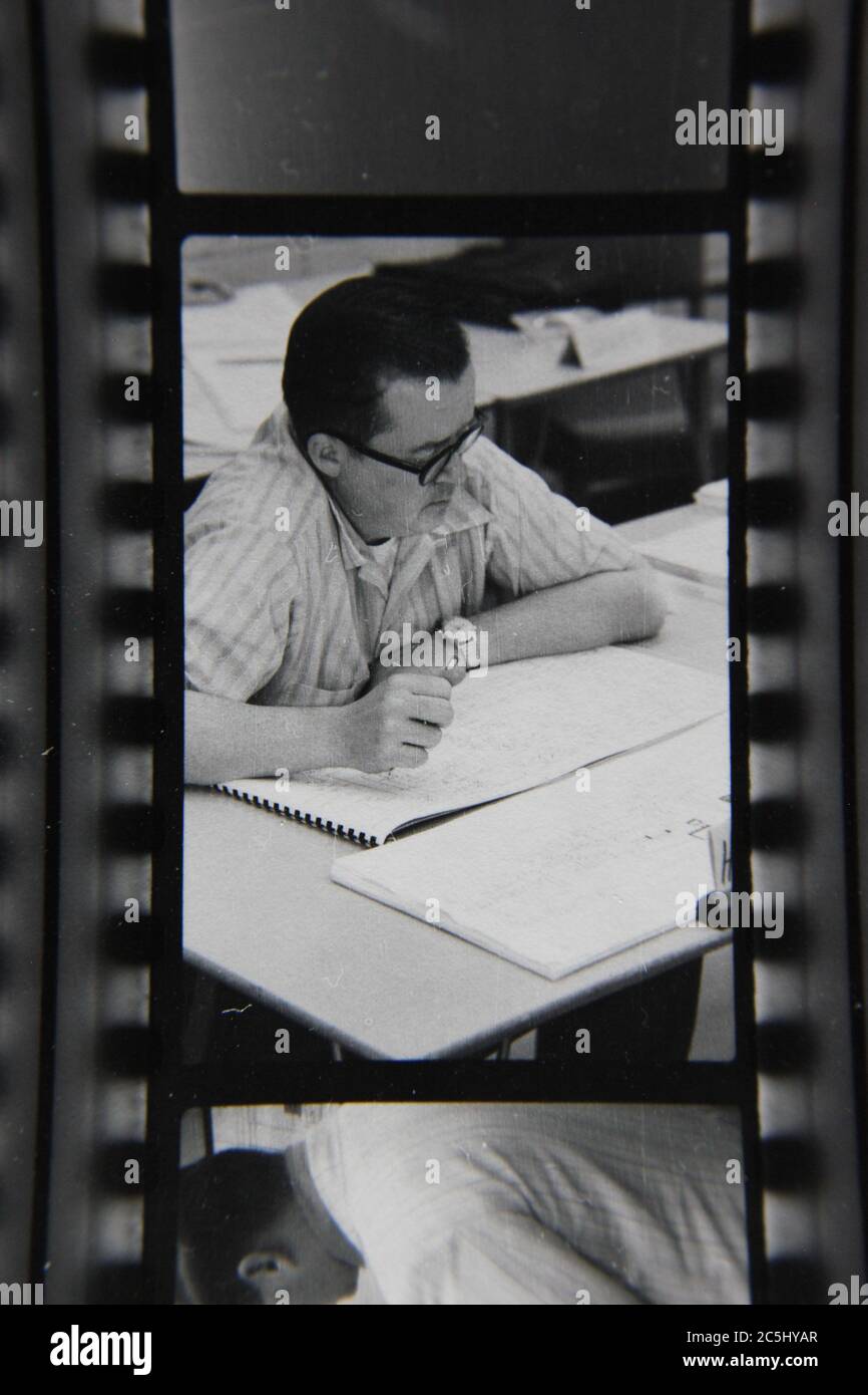 Fine anni '70 vintage contatto stampa in bianco e nero fotografia di un uomo che scrive su un sacco di documenti. Foto Stock