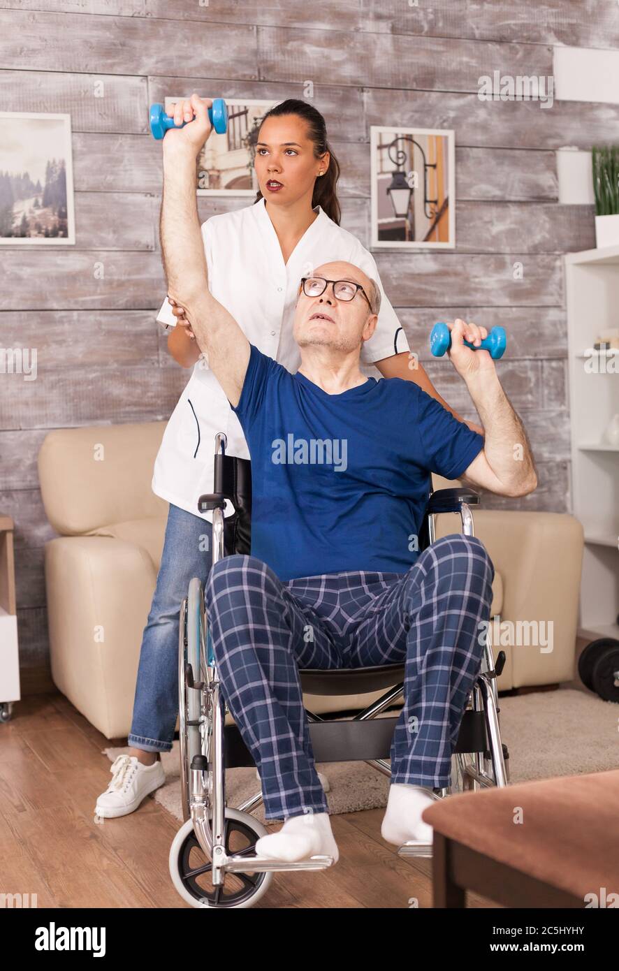 L'uomo anziano che fa esercizi durante la riabilitazione aiutato da un medico. Disabili anziani disabili con lavoratore sociale in recupero terapia di supporto fisioterapia sistema sanitario di cura casa di riposo Foto Stock