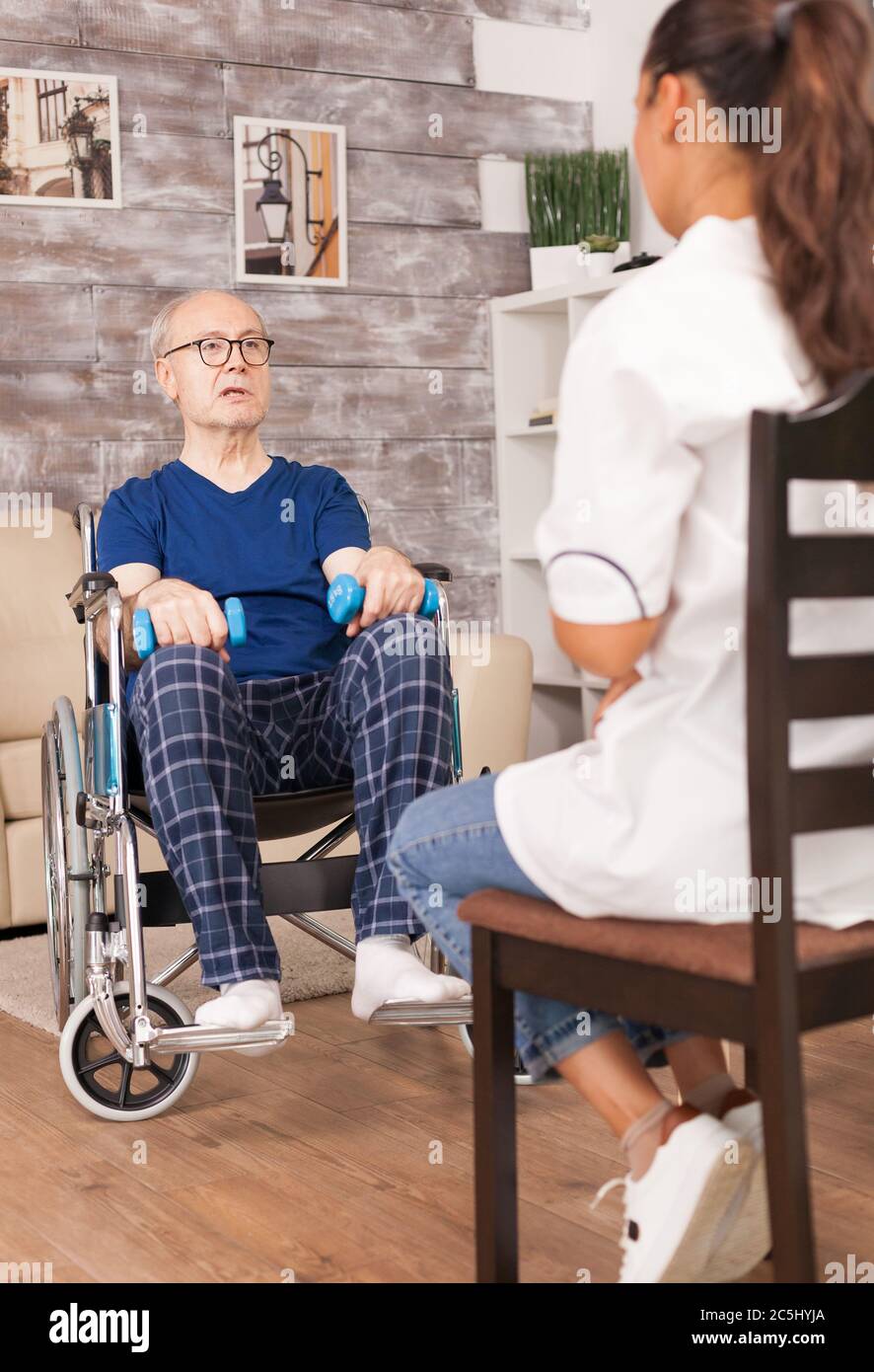 Caregiver che aiuta l'anziano ad addestrare le braccia. Disabili anziani disabili con lavoratore sociale in recupero terapia di supporto fisioterapia sistema sanitario di cura casa di riposo. Foto Stock