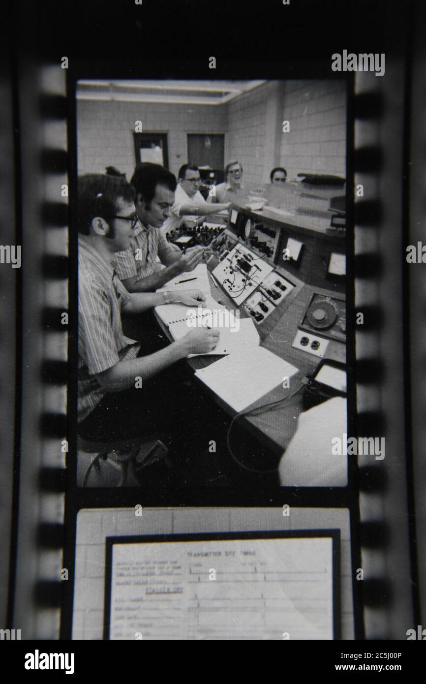 Fine anni '70 vintage contatto stampa in bianco e nero fotografia di un gruppo di uomini che gestiscono un super computer. Foto Stock