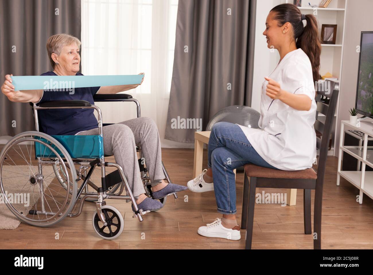 Medico che fa riabilitazione con la donna anziana in sedia a rotelle. Formazione, sport, recupero e sollevamento, casa di riposo per anziani, assistenza sanitaria, assistenza sanitaria, assistenza sociale, medico e assistenza domiciliare Foto Stock