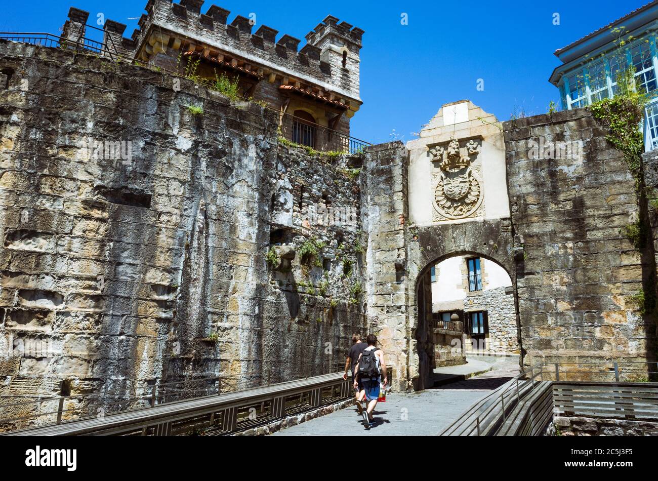 Hondarribia, Gipuzkoa, Paesi Baschi, Spagna - 11 Luglio 2019 : due giovani camminano attraverso la porta di Santa Maria, l'accesso principale all'Alde Zaharra Foto Stock